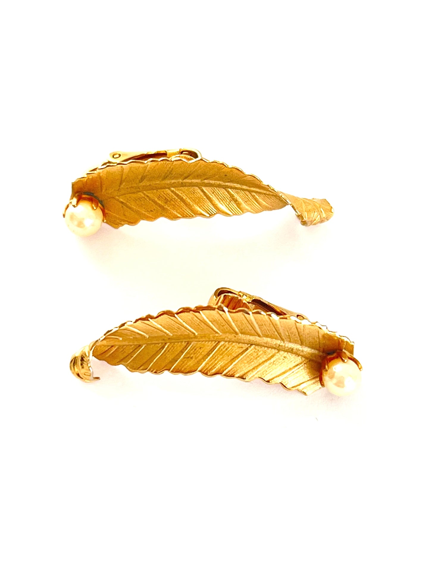 Pair of gold feather-shaped earrings on a white background