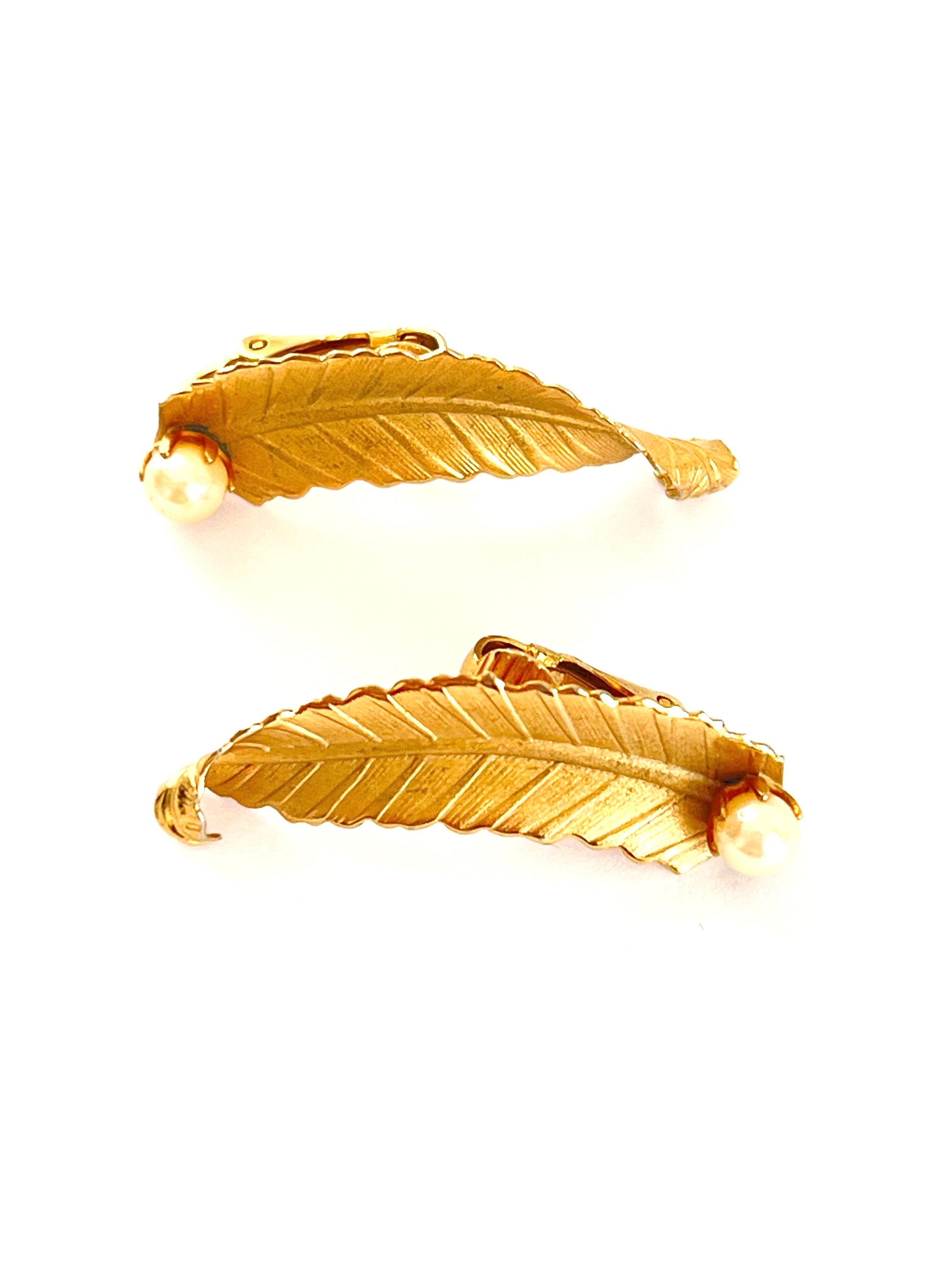 Pair of gold feather-shaped earrings on a white background