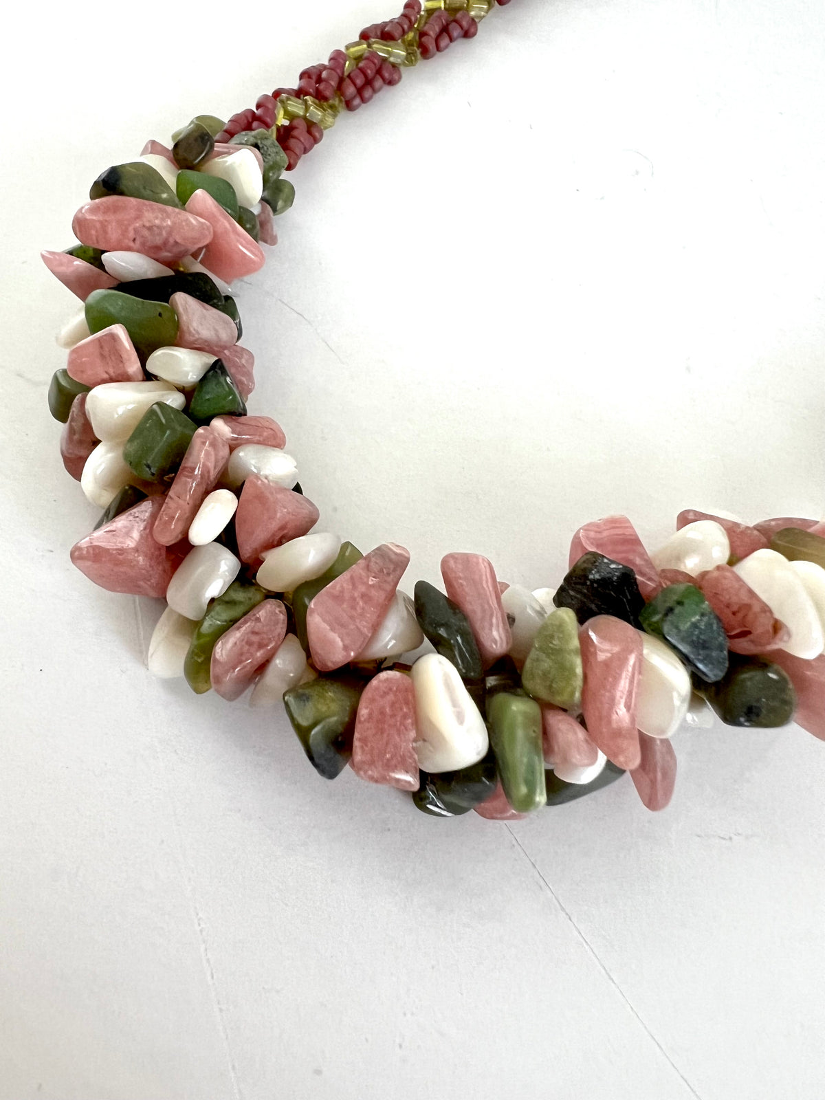 A chunky tumbled stone necklace featuring a mix of pink, green, and white stones, photographed on a plain white background.