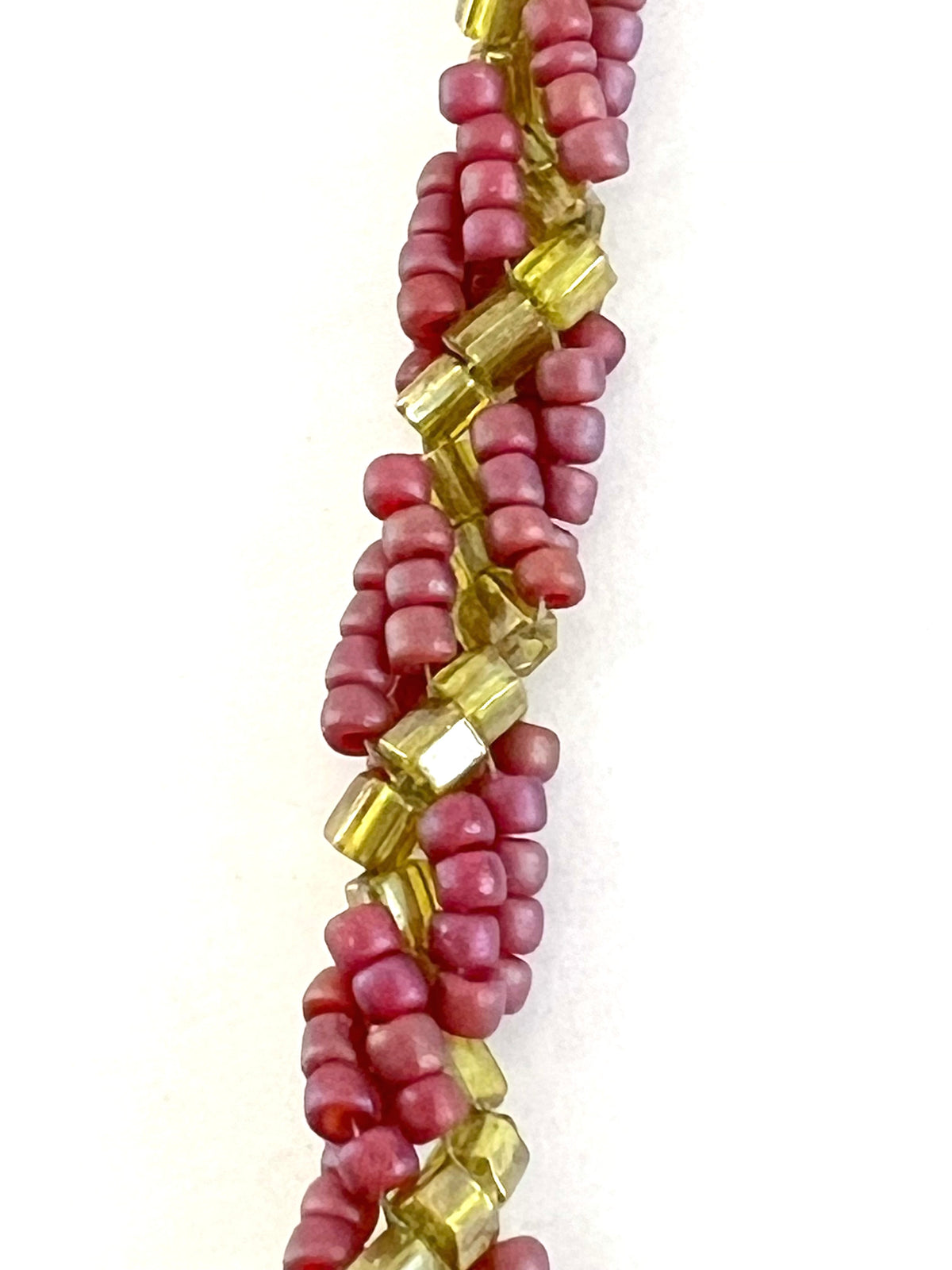 A close-up of a beaded strand featuring alternating rows of faceted translucent yellow beads and matte dusty pink round beads, set against a plain white background.