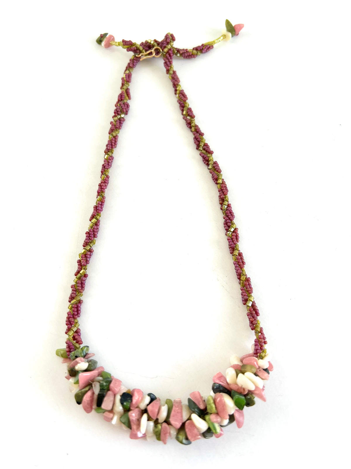 A handmade beaded necklace featuring a braided cord of magenta and olive green beads with a chunky collar of polished pink, white, and green stone chips, displayed on a clean white background.