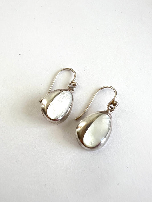 A pair of silver teardrop dangle earrings with Mother of Pearl centers, displayed on a plain white surface.